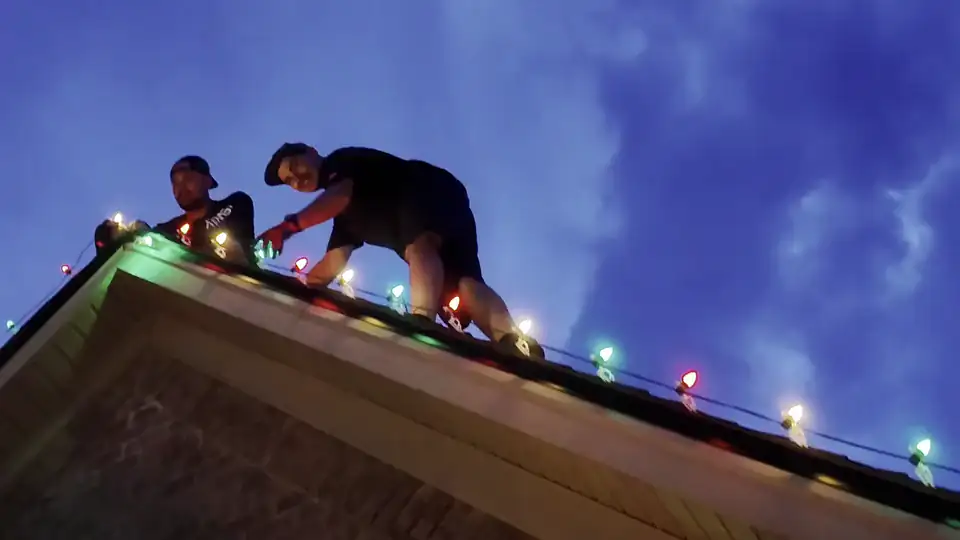 Two Hisway Lighting crew members clipping C7 bulbs along a ridge at dusk
